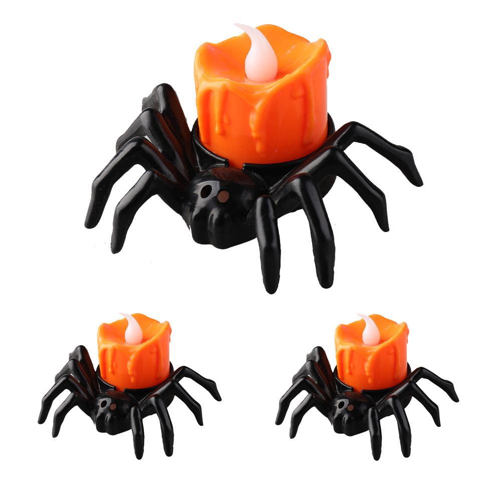 Orange spider-shaped LED candle light with realistic flame effect for Halloween decoration on a table.