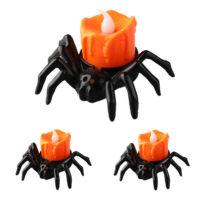 Orange spider-shaped LED candle light with realistic flame effect for Halloween decoration on a table.